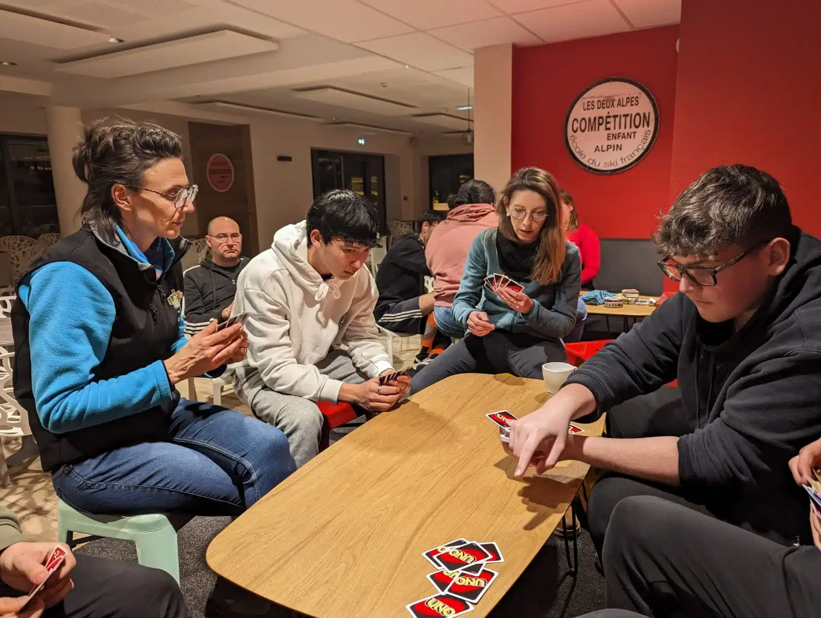 des jeunes jouent aux cartes uno autour d une table en bois