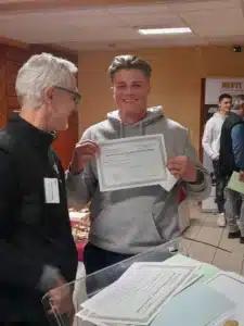 un jeune homme souriant recoit un diplome du baccalaureat te